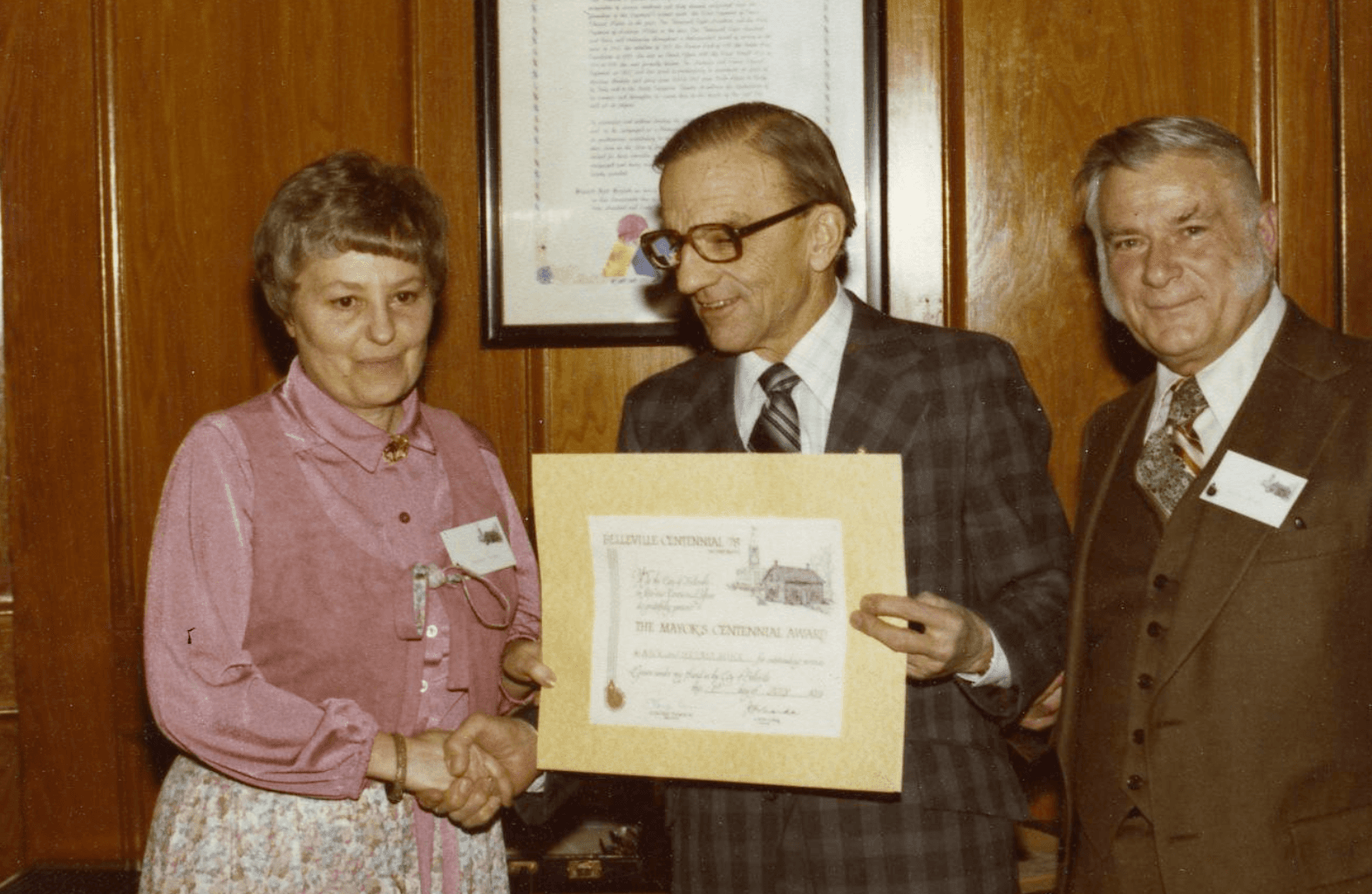Old photo shows a person receiving an award recognizing them for excellence.