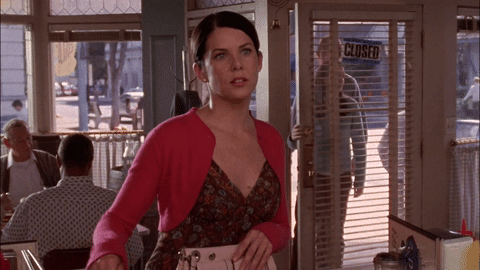 Brunette woman in pink top winking at diner counter.